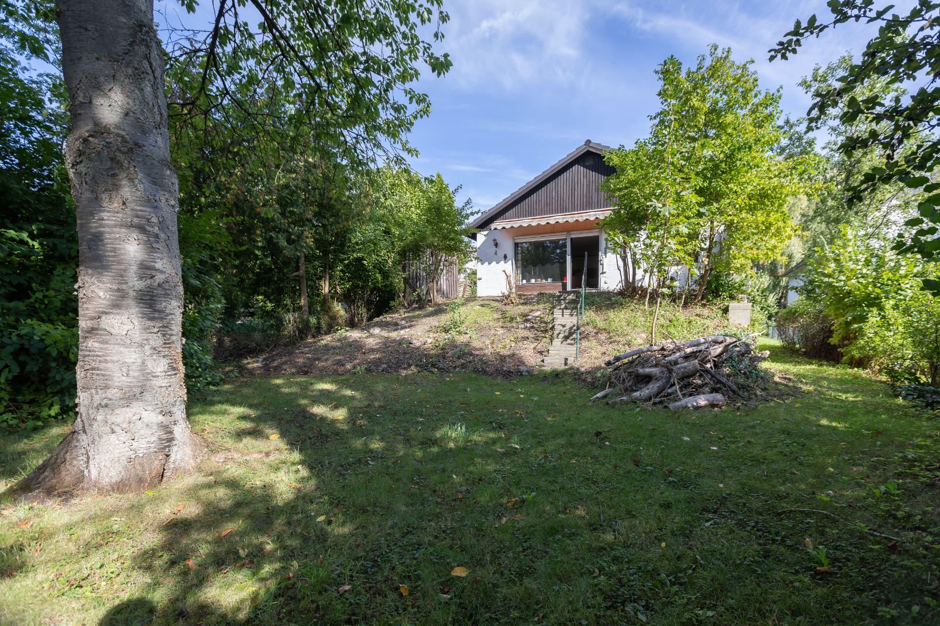 Blick über die Gartenfläche zum Altbestand mit Terrasse