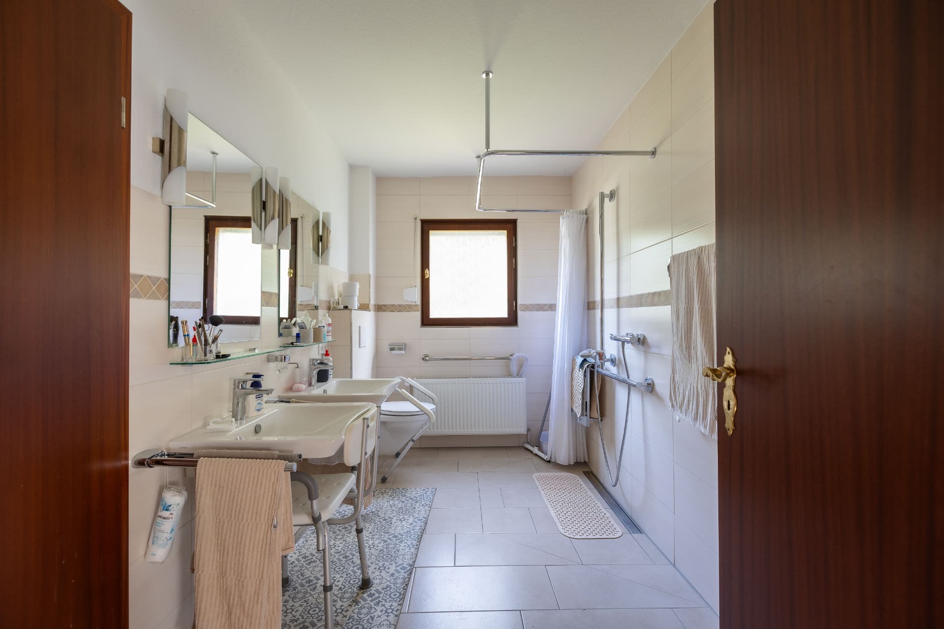 Großes, barrierearmes Badezimmer mit zwei Waschbecken und ebenerdiger Dusche