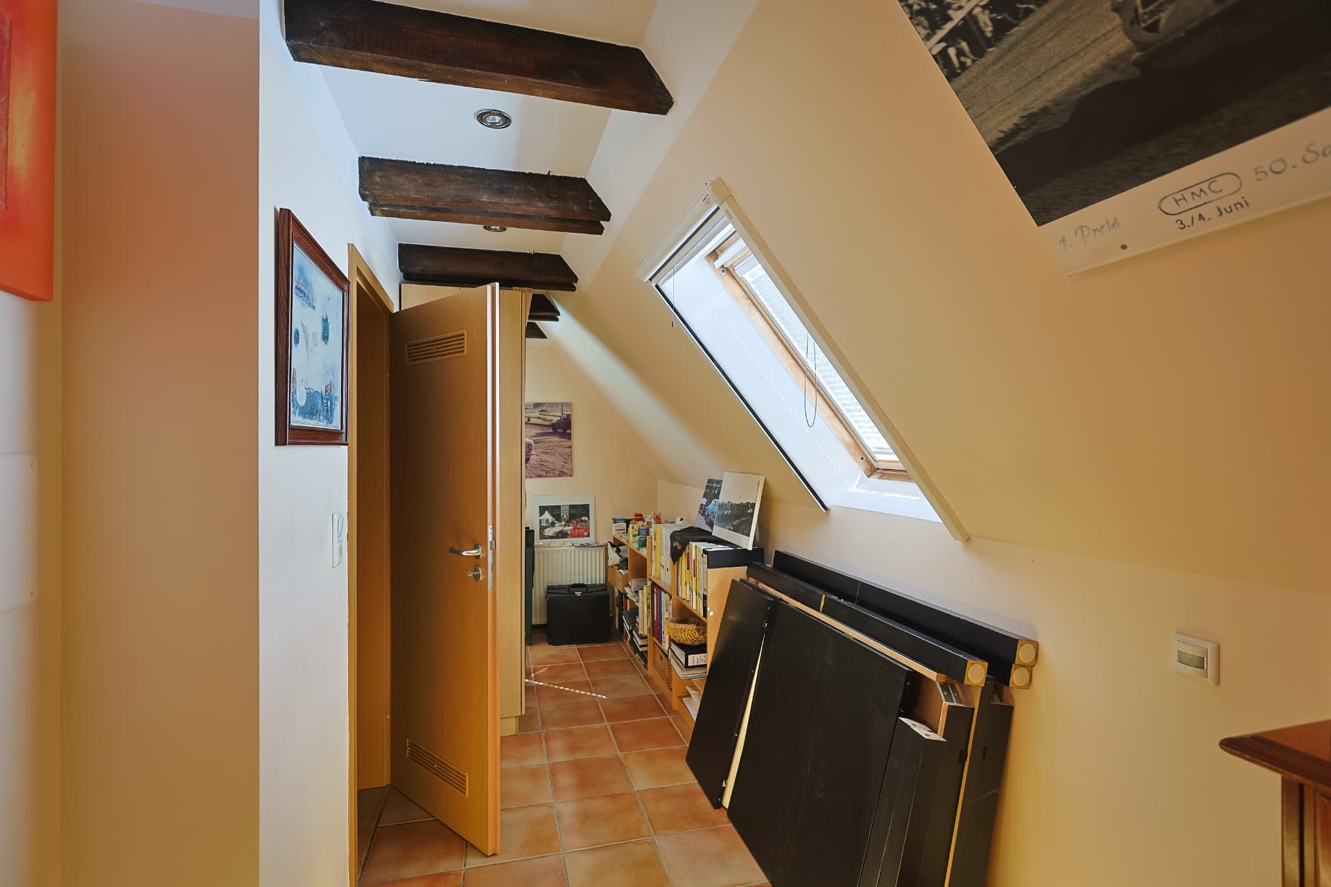 Ausgebautes Dachgeschosszimmer mit sichtbaren Balken und Dachfenster