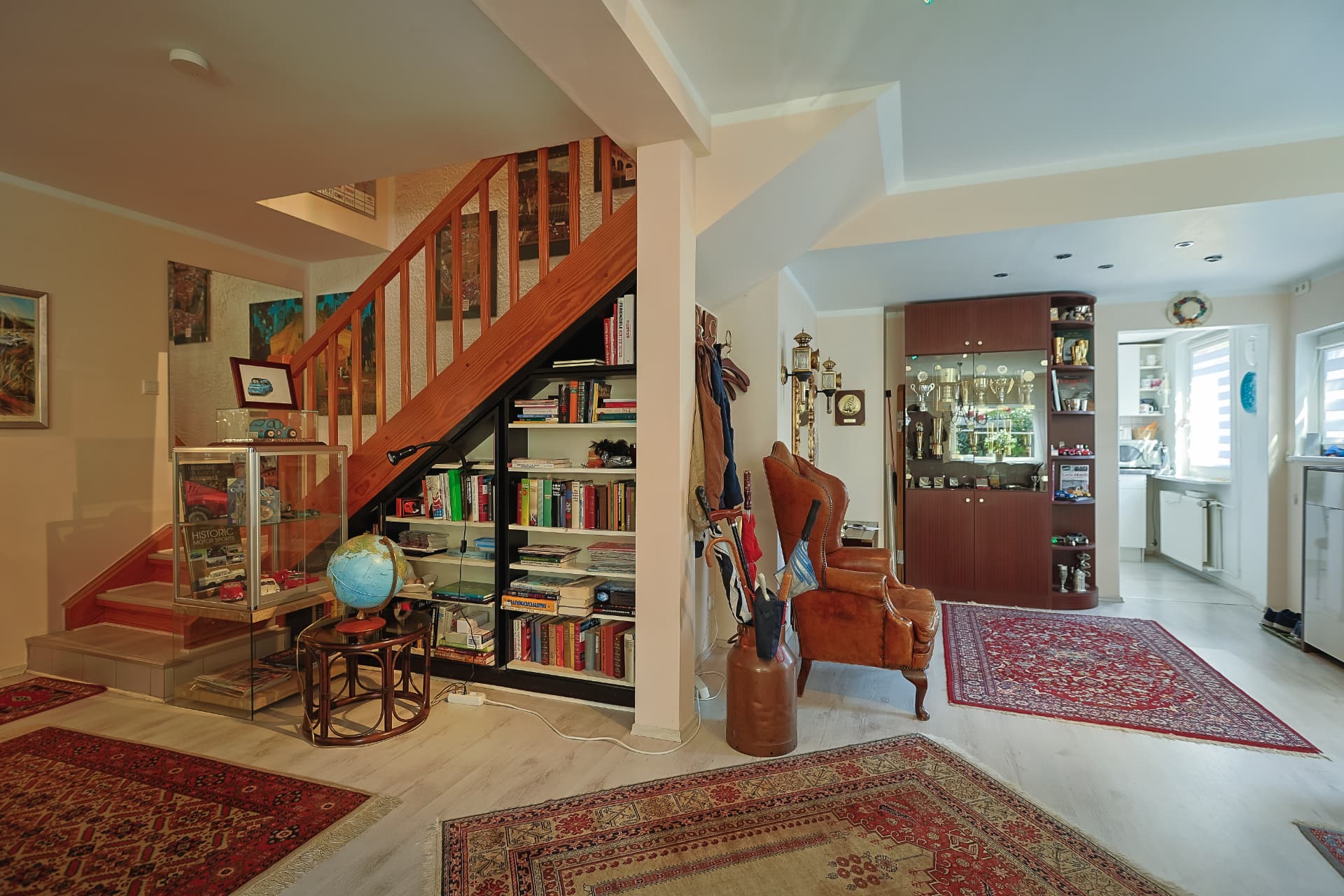 Flur mit Holztreppe, Bücherregal und Blick in die Küche