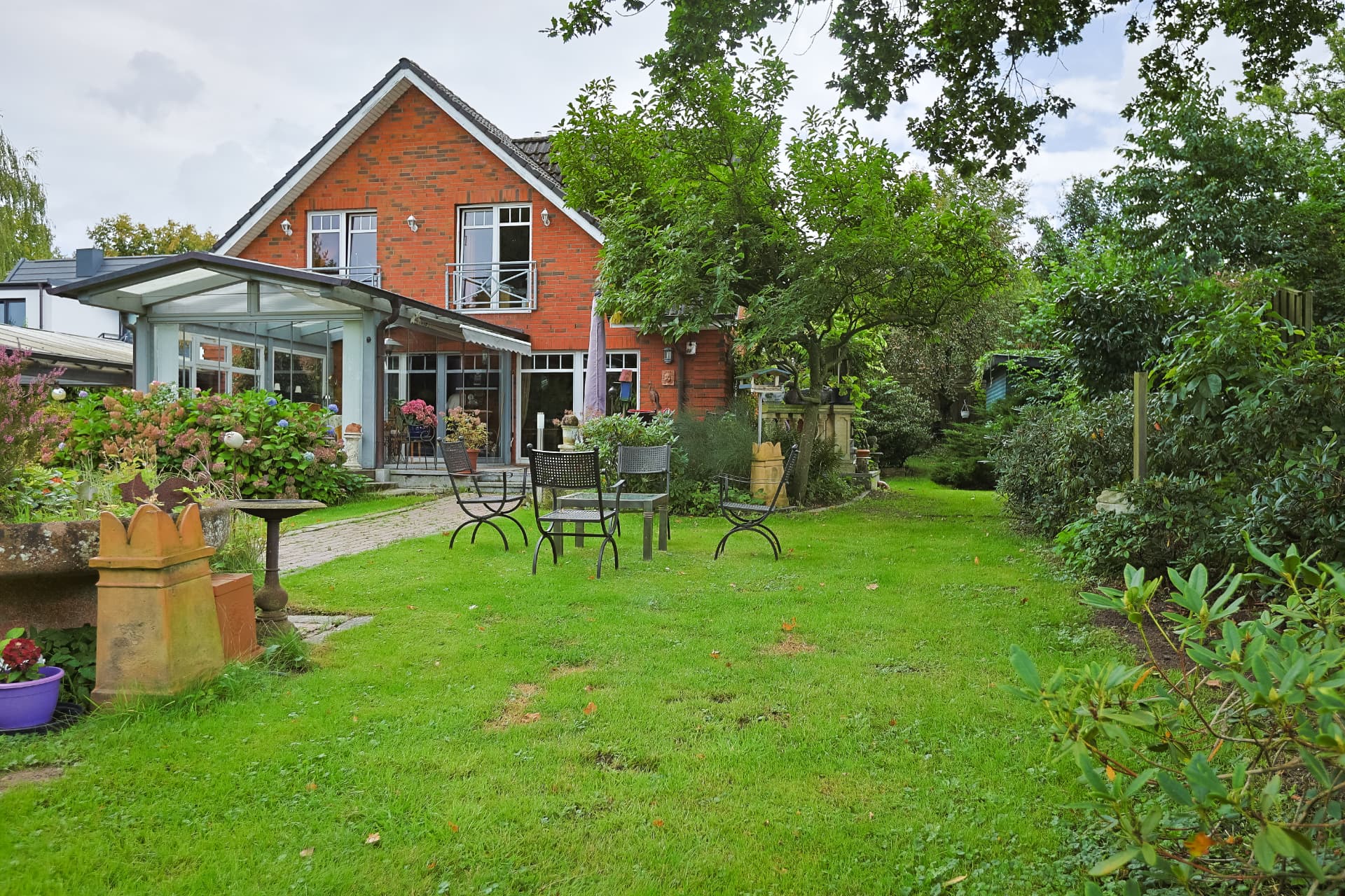 Gartenansicht des Backsteinhauses mit Wintergarten und Sitzplatz